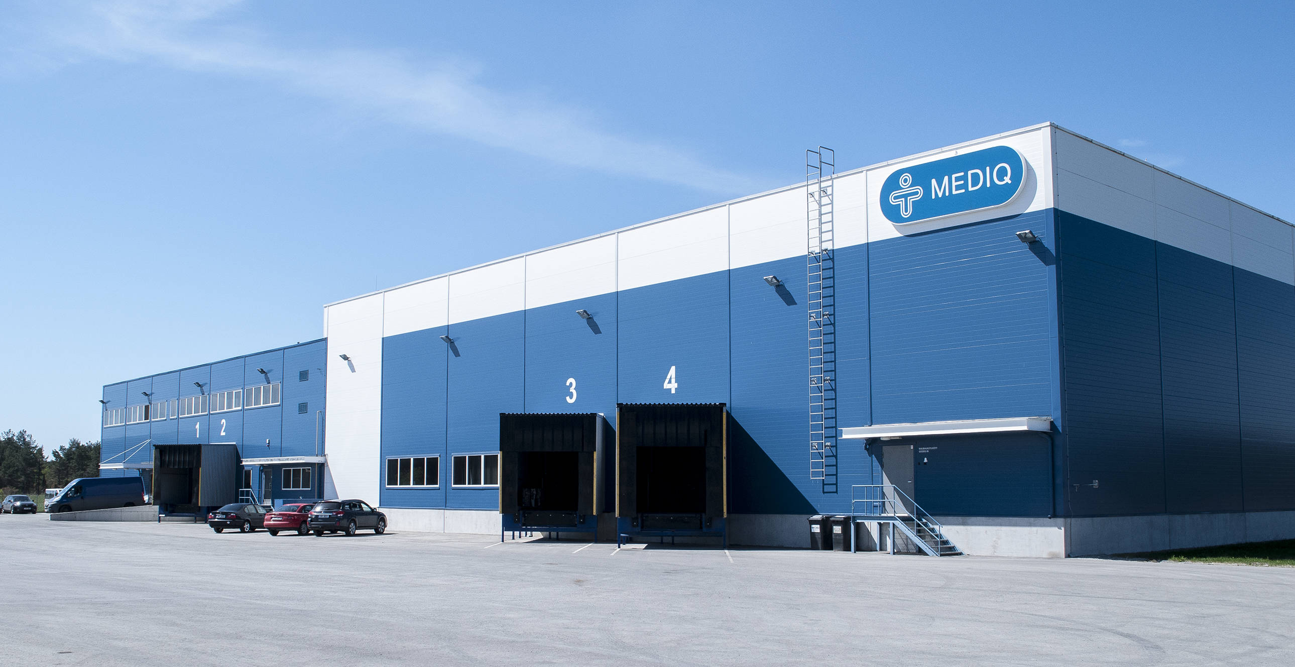 A blue colored main building of Mediq Eesti OÜ, in front of which employees' cars are parked